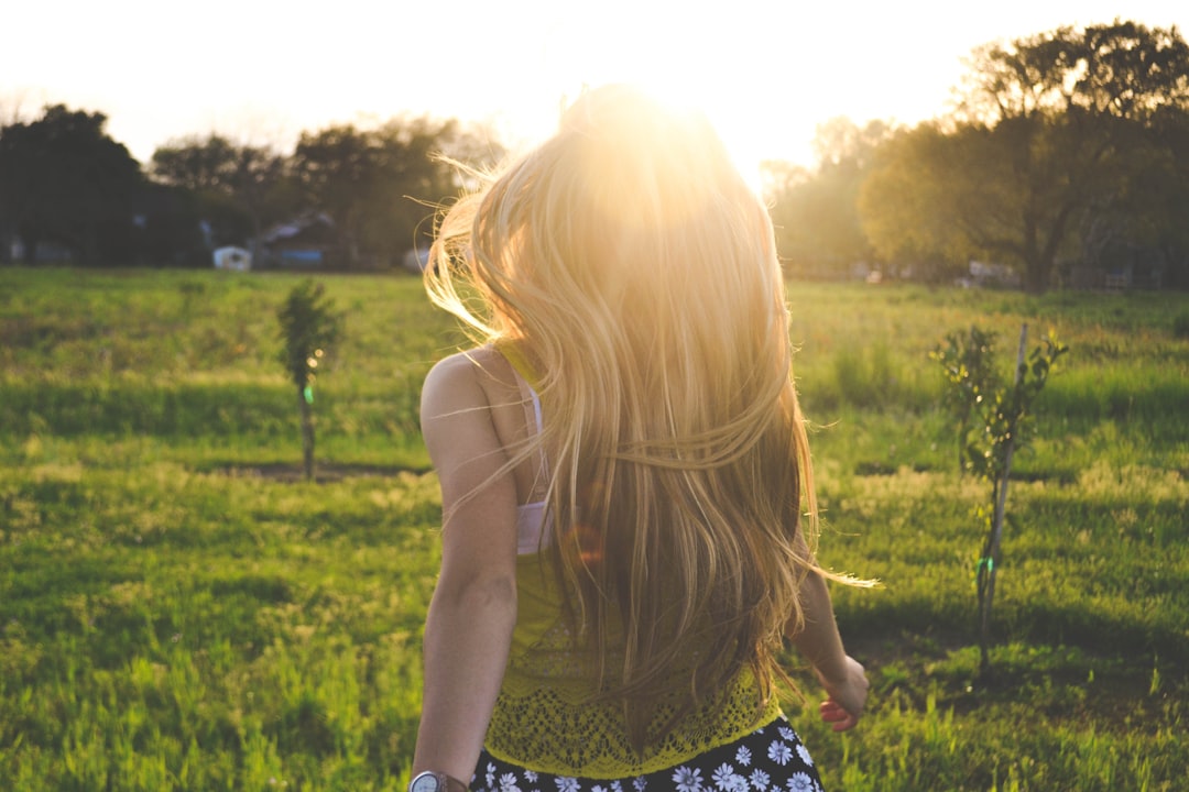 Sunlight welcomes blonde girl by Athletic Brands woman walking on lawn with trees
