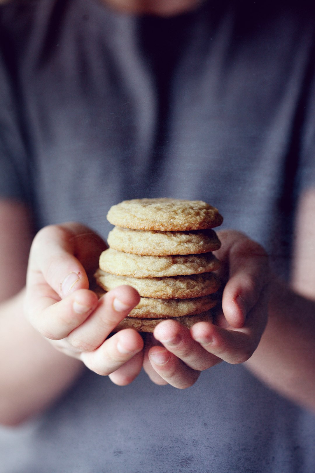 Child holding freshly baked sugar cookies. by Athletic Brands person holding brown cookies in close up photography